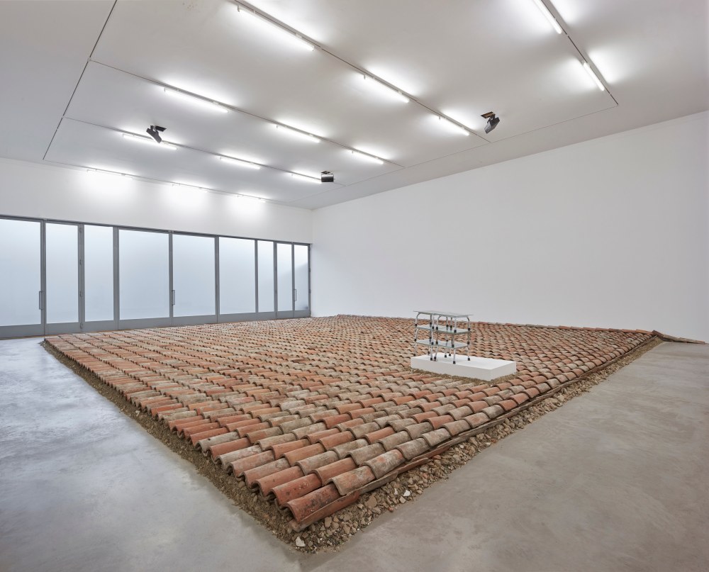 Reinhard Mucha,&amp;nbsp;Island of the Blessed, [2024] 2016, 2-part in-situ sculptural room installation.&amp;nbsp;Island of the Blessed, 2016, Overlapping clay roof tiles, construction rubble (found objects), white pedestal, steel tape measure, 6 step stools, 6 float glass panes, audio equipment (sound track of starting airplanes), 47.2 x 480.3 x 496 inches (120 x 1220 x 1260 cm).&amp;nbsp;Ostende &amp;ndash;&amp;nbsp;K&amp;ouml;lner Stra&amp;szlig;e 170, 2006, 2014, Paper tape, UV-protection glass, museum board, archival pigment print, 15.67 x 20.67 x 0.71 inches (39.8 x 52.5 x 1.8 cm). Courtesy of Galleria Lia Rumma, Milan/Naples. Photo: Agostino Osio.