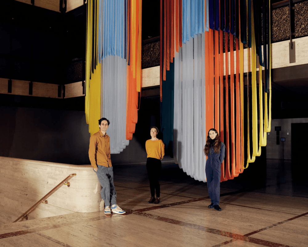 3 people standing in front of a vertical ribbon backdrop