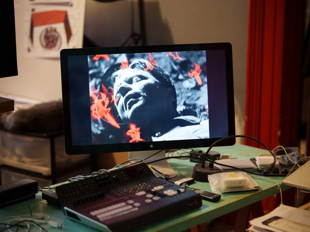 A desk with monitor and video editing equipment in an artist's studio