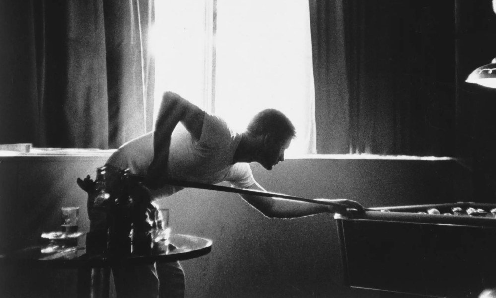 Black and white photo of a young man playing pool