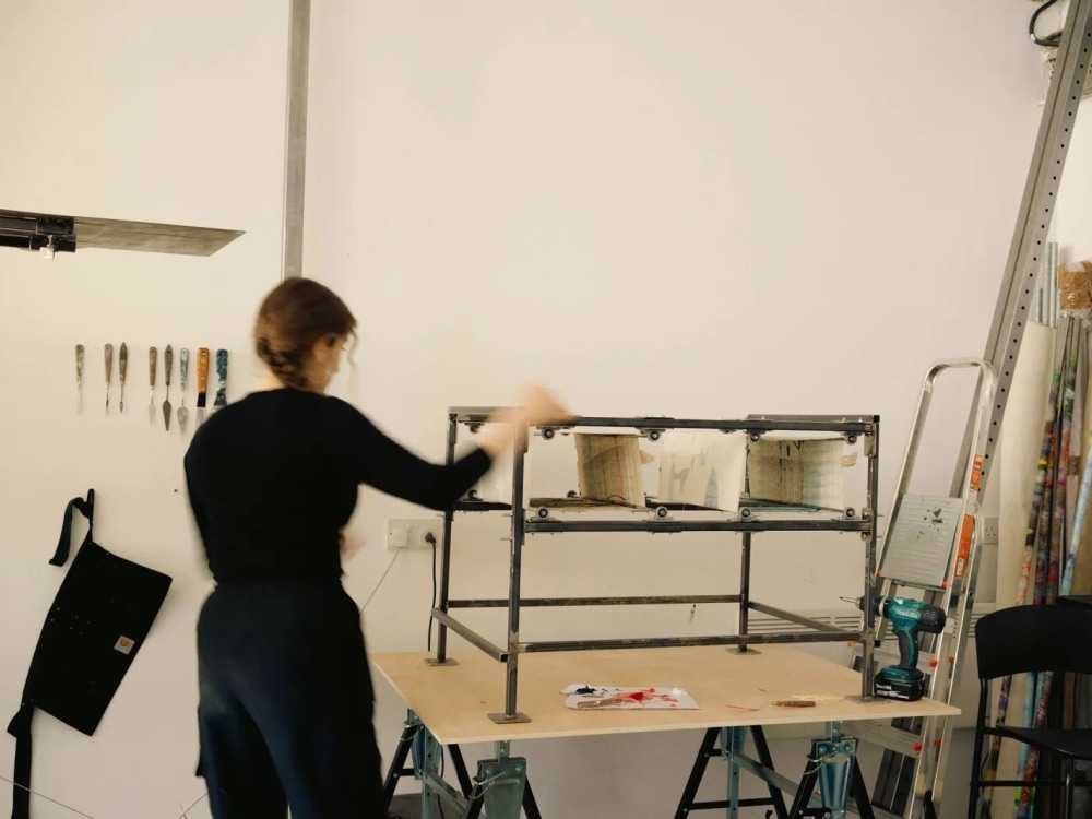 A female artist in her studio creating a painting using a cube-like structure