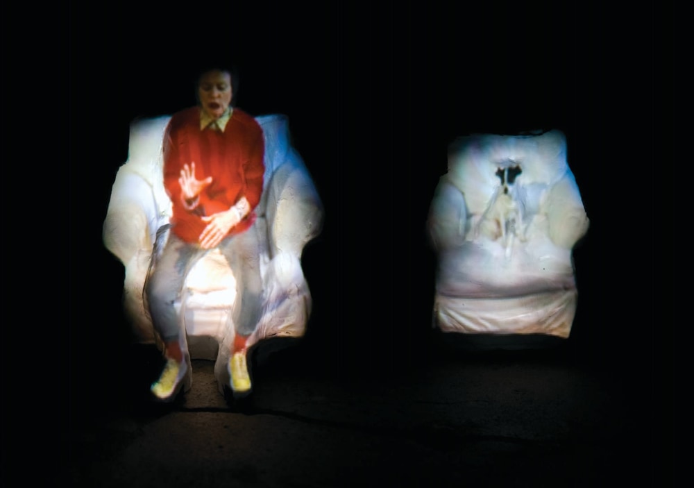 Still from Laurie Anderson's video work "From the Air" showing herself projected onto clay figures
