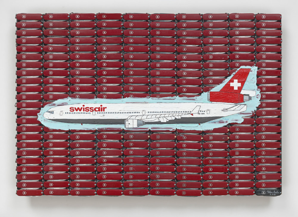 A Swissair airplane painted over a group of red Swiss Army knives on plywood by Tom Sachs