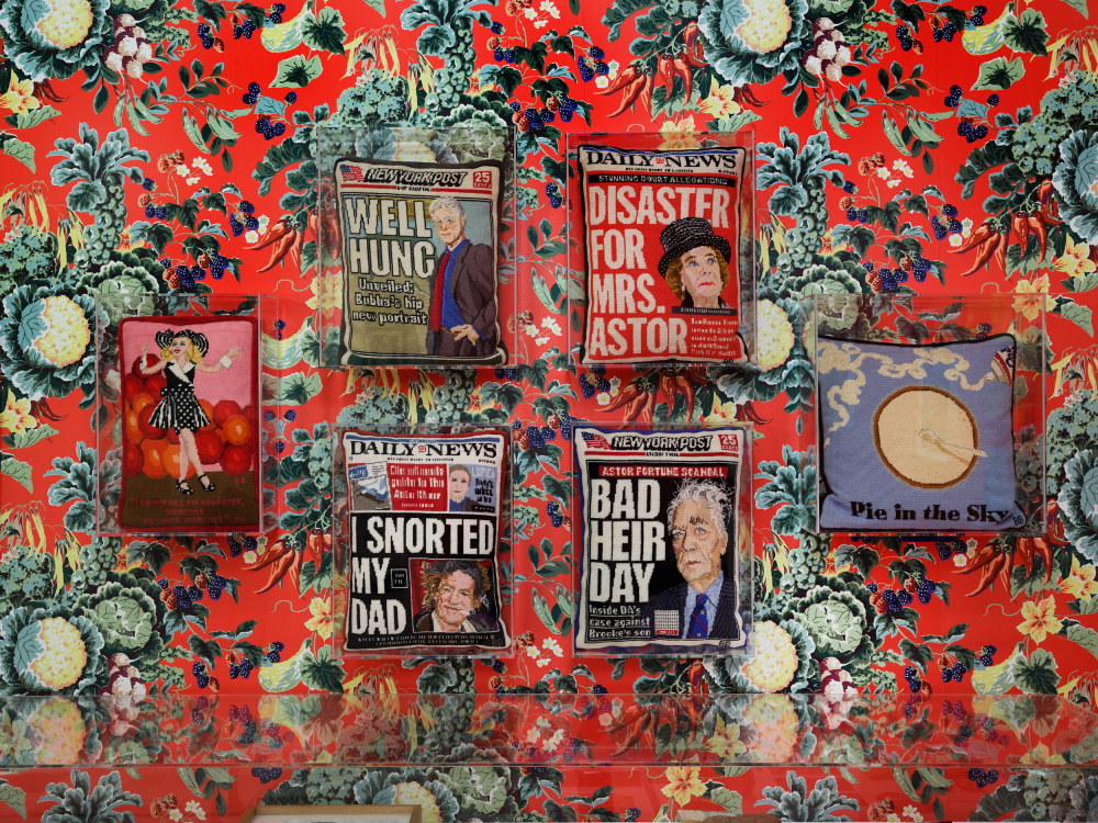 Needlepoint pillows of tabloids displayed on cauliflower wallpaper