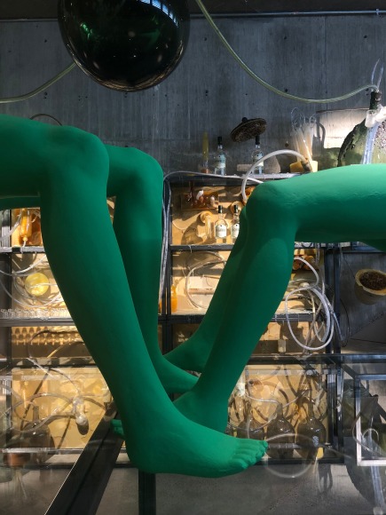(Description: green female mannequin on illuminated platform)