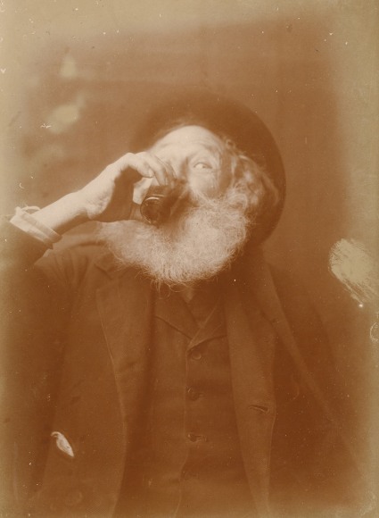 Warm toned antique photo of a bearded man drinking wine, his eye catches the camera.