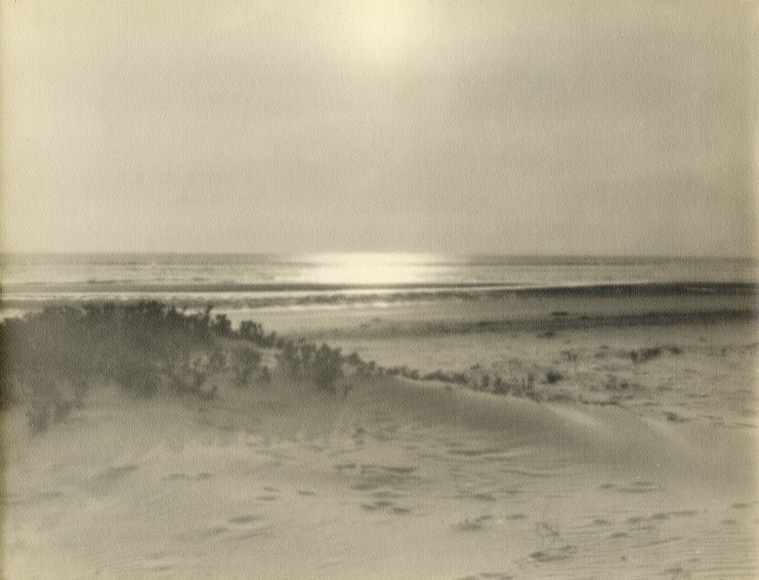 Warm toned photographic seascape with natural beach and dunes in foregournd.