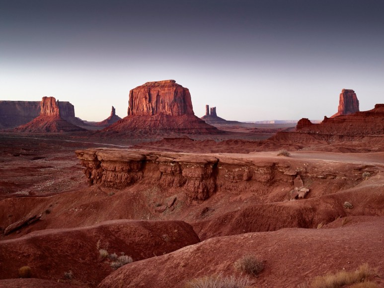 Color photograph of the famous Monument Valley buttes at dawn.
