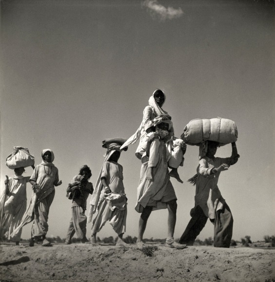 Low angle black and white photo of refugees walking though the desert.