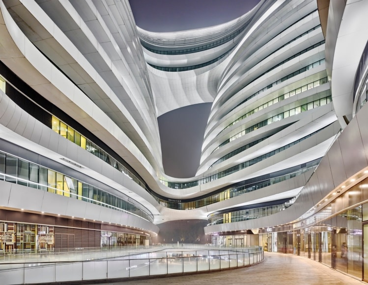 Color photo of a curved and futuristic looking building seen at night
