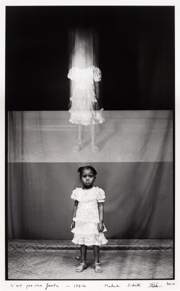 Double frame black and white image of a young African girl having her portrait taken, the top image is blurred.