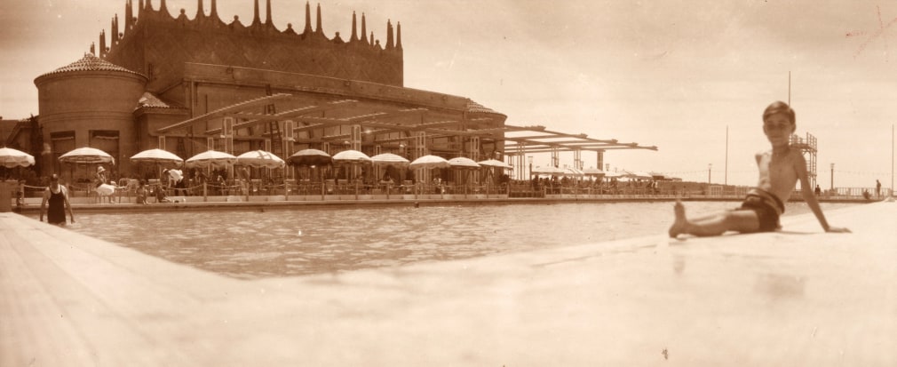 Warm toned back and white photo of a young boy lounging by pool at a resort on the French Riviera.