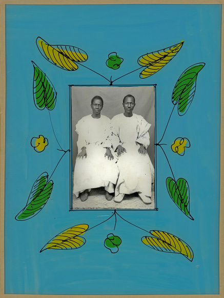 Black and white photo portrait of two African men, in a blue hand painted frame with a green and yellow leafy design.