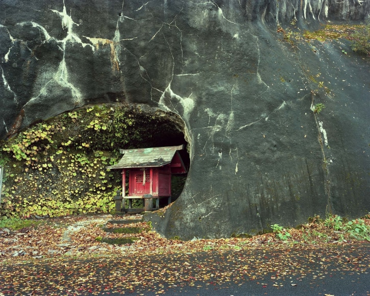 Small red Japanse shrine, set into a large rock.