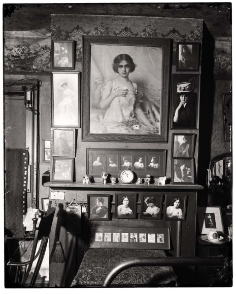 Vintage black and white photo of a mantel surrounded by female portraiture.