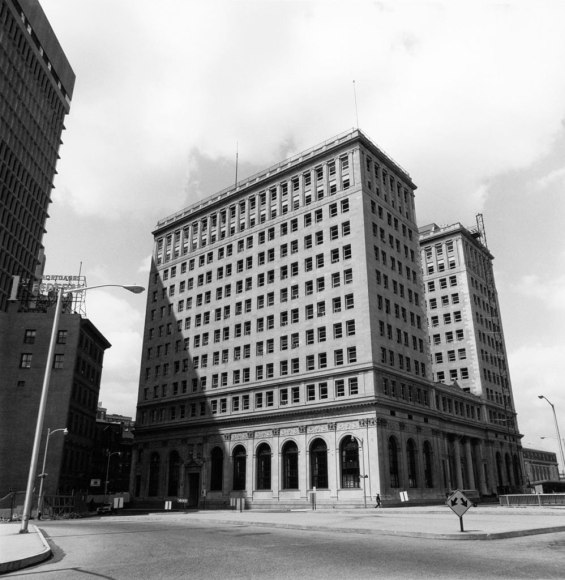 Black and white photo of a large early 20th century building in a deserted corner of a downtown area.