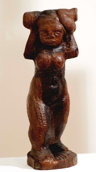 Medium brown, wooden sculpture with pock mark detailing of a rounded female form carrying a small childlike form upon her shoulders and behind her face.