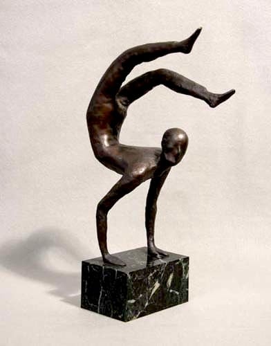 Dark, smooth, metal sculpture of a lanky humanoid figure balancing on their hands with their legs swung in a crescent shape above their head. The face has no defining facial features and is looking towards us. The sculpture is mounted on a black marble block.