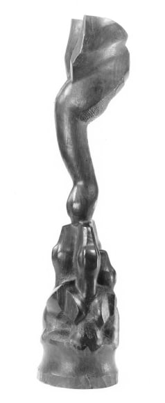 Photo of a thin, tall sculpture of a large, triangularly shaped bird with its beak in the center of a crowd of three smaller birds. The birds are crafted in geometric, pointy shapes.