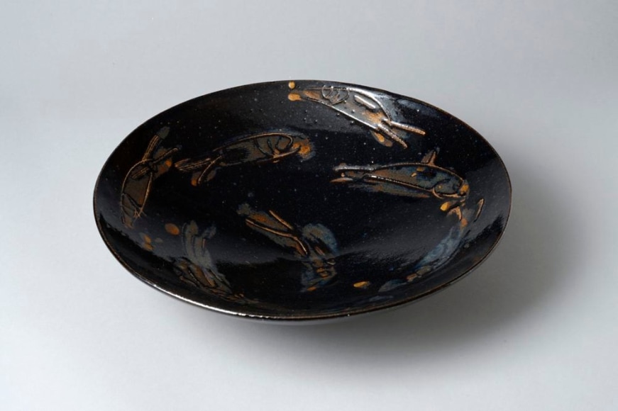 Persimmon on black-glazed large shallow bowl with dog-like animal patterning