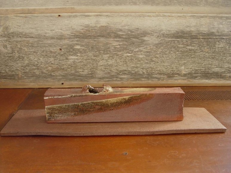 Rectangular sculpted container rests on a flat base, titled TAIRAGI, 2010