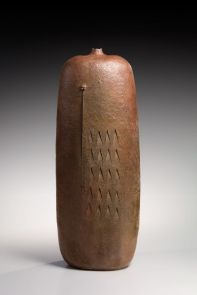 Monumental oblong ash-glazed vessel with small, raised, torn mouth with carved abstract bird design