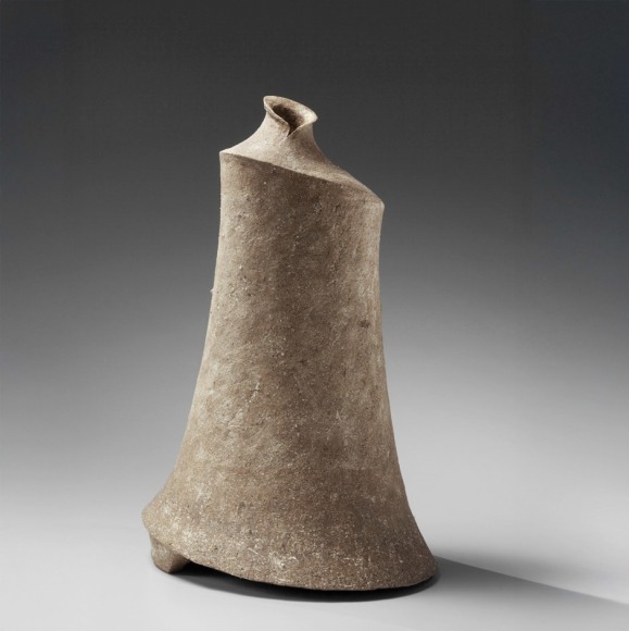 Tall gray columnar sculpture with sloped shoulders, flaring base and bottle-like mouth, 2012