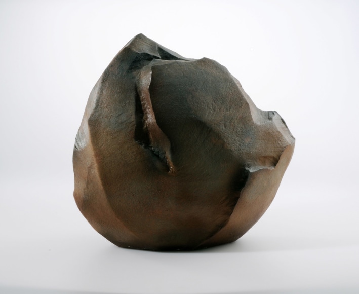 Large rounded rock-like sculpture with slip glaze in tones of brown, gray and rust 