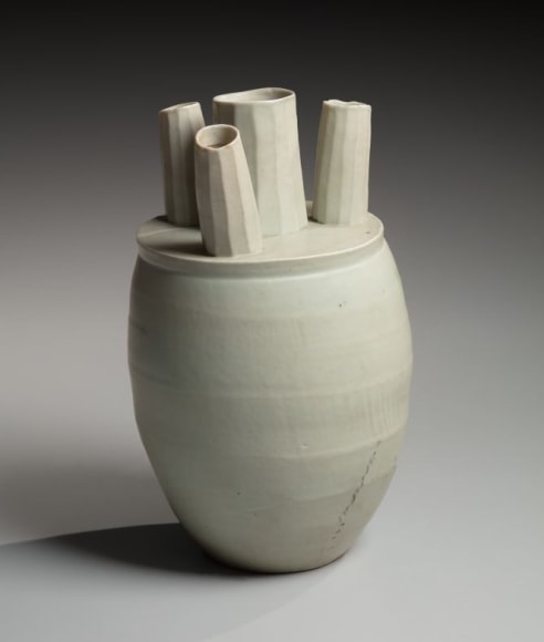 Conical covered wheel-thrown form with four fluted protruding pipes at top