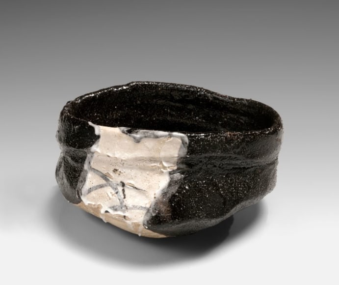 Black Oribe (kuro-oribe) clog-shaped teabowl with white square and lattice pattern under the glaze