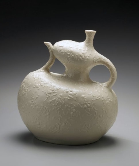 Attenuated and animated pouring vessel with surface decoration of dancing figures in relief