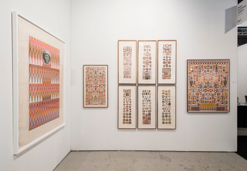 Installation view of an art fair booth, showcasing paintings, collages,  on the walls.