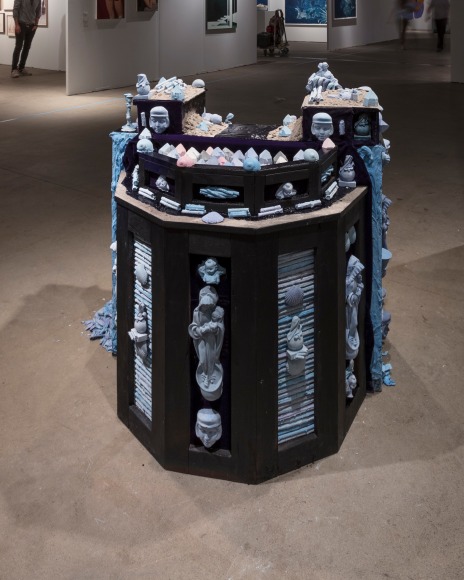 Installation view of an open art fair booth, showcasing a large &quot;wishing well&quot; installation on the floor.