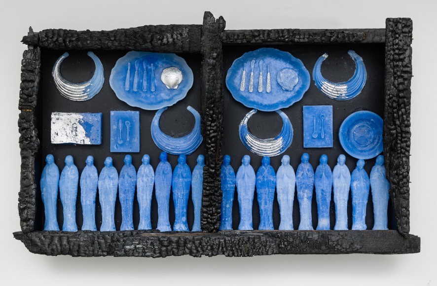 A rectangular artwork with charred wood and wax on the wall