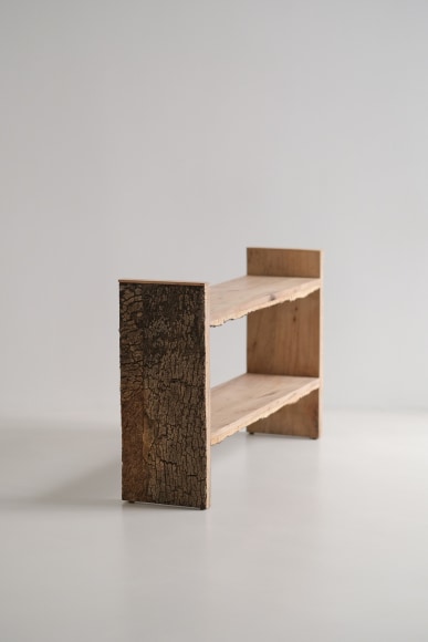 Bookshelf made of oak and cork standing against a grey background.