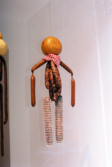 Exterior view of saucissons and scamorza&nbsp;figure with plaid cloth levitating in the window. Photo by Adrianna Glaviano&nbsp;