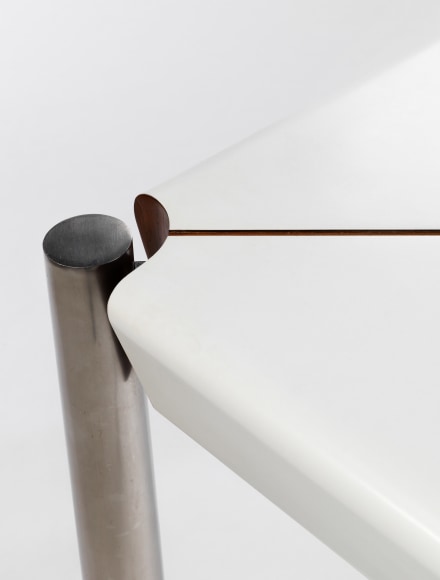 Detail view of corner where white formica table meets stainless steel legs