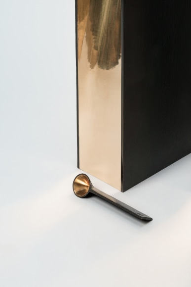 bronze with beeswax candle holder photographed on a grey background.