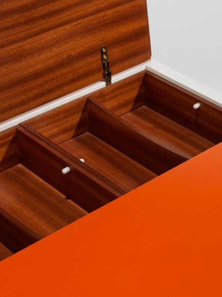 photograph of low table by Motte in a blank room, top of table is half orange and half white
