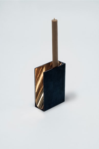 bronze with beeswax candle holder photographed on a grey background.