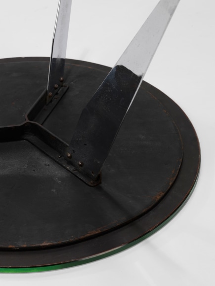 photograph of table in a blank room with metal legs and a glass top