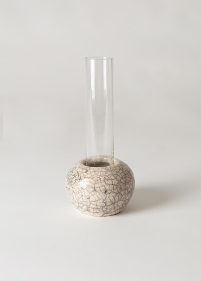 CLEAR glass tubular vase sitting inside raku ceramic holder.