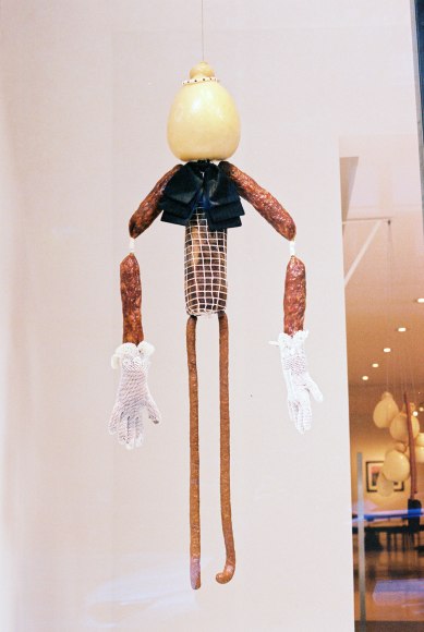 Exterior view of saucissons and scamorza&nbsp;figure wearing a black ribbon tie levitating in the window. Photo by Adrianna Glaviano&nbsp;