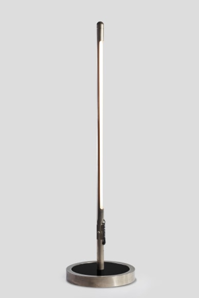 photograph of long metal floor lamp in a blank room