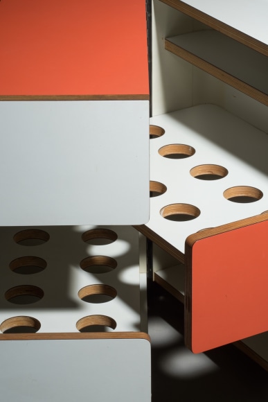Bar cart in orange and white shown open and closed with different holes for various parts.
