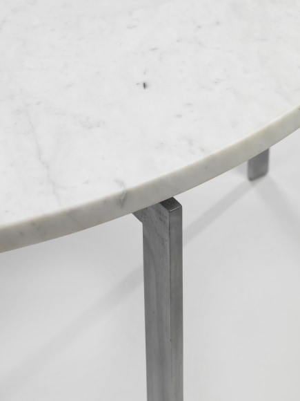 photograph of a table with steel legs and a marble top in a blank room
