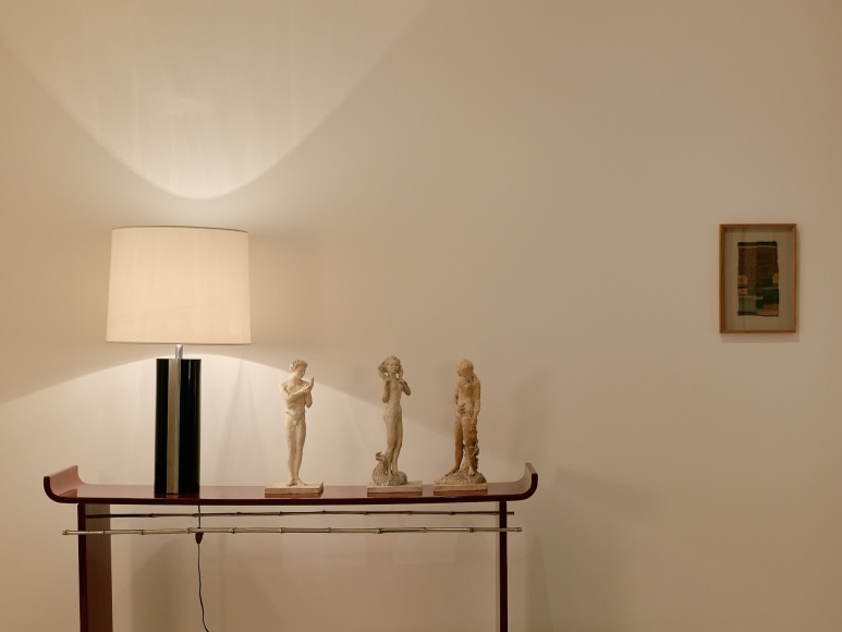 installation view of sheila hicks minime in the gallery beside a Maria Pergay red lacquer table.