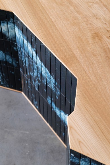 Desk made of oak and tiles by made in situ . Blue and brown sitting in a grey room.