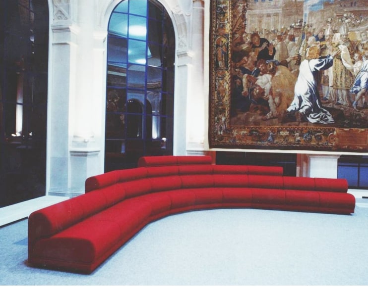 Archival image of Hotel de Ville sofa by Pierre Paulin. Image of sofa in room with tapestry.