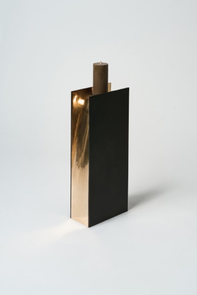 bronze with beeswax candle holder photographed on a grey background.